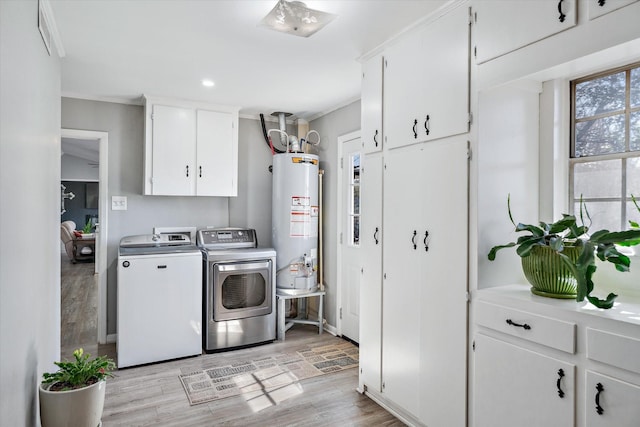 laundry room with cabinet space, washer and clothes dryer, ornamental molding, light wood-type flooring, and gas water heater