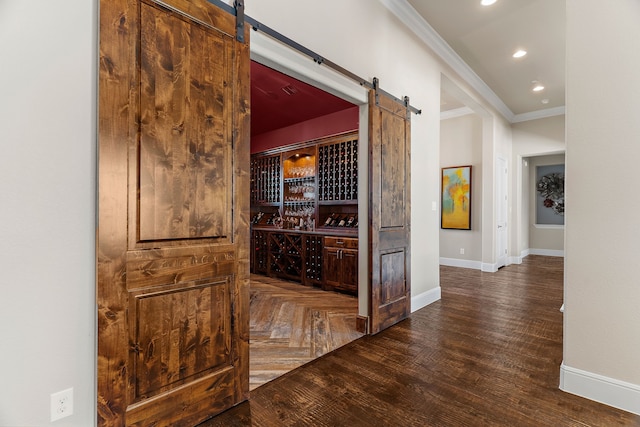 wine area with crown molding, recessed lighting, a barn door, baseboards, and parquet flooring