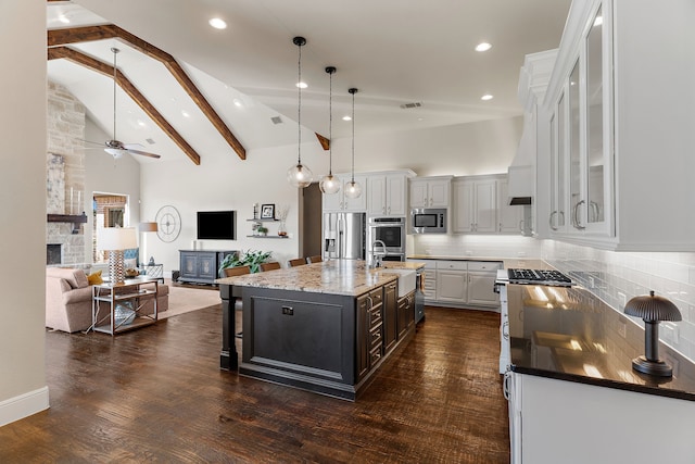 kitchen with decorative backsplash, stainless steel appliances, a stone fireplace, high vaulted ceiling, and a sink