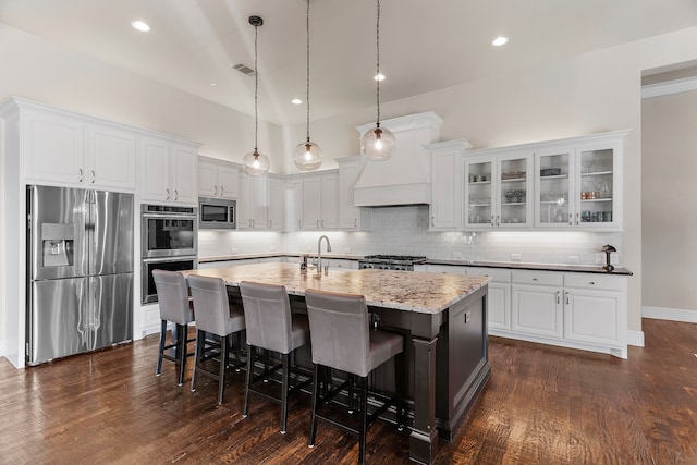 kitchen with a center island with sink, visible vents, white cabinets, decorative backsplash, and stainless steel appliances