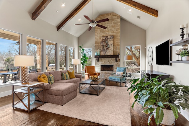 living area with high vaulted ceiling, beam ceiling, a stone fireplace, and wood finished floors