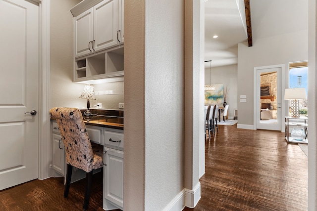 home office with dark wood-style floors, baseboards, and built in desk