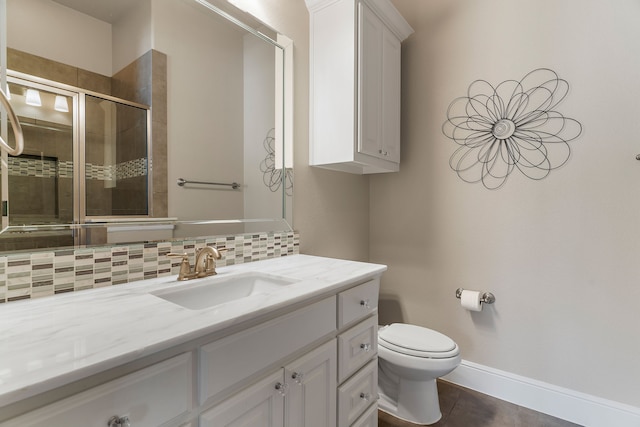 bathroom with tasteful backsplash, baseboards, toilet, vanity, and a shower stall