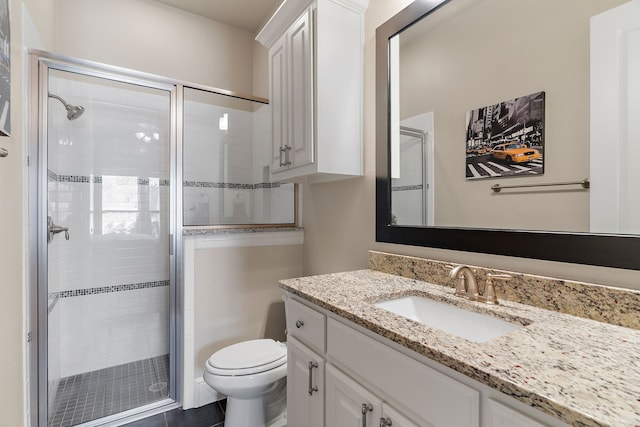 bathroom with a stall shower, vanity, and toilet