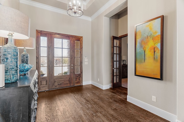 entryway with ornamental molding, dark wood-type flooring, baseboards, and an inviting chandelier