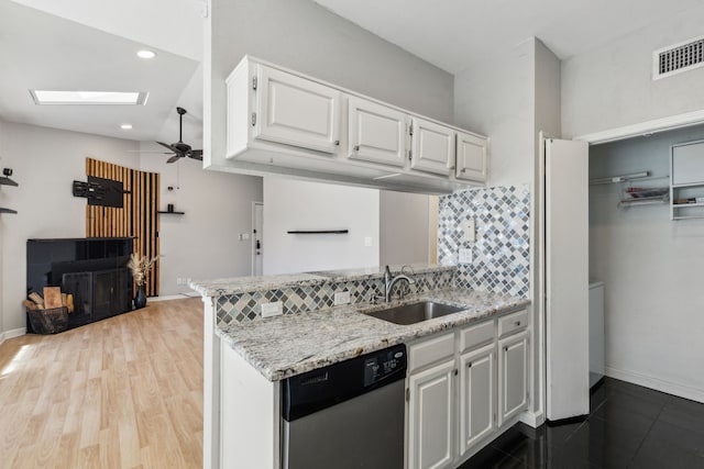 kitchen with visible vents, white cabinetry, a sink, dishwasher, and a peninsula