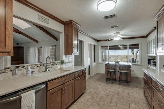 kitchen with a sink, visible vents, light countertops, stainless steel dishwasher, and decorative backsplash