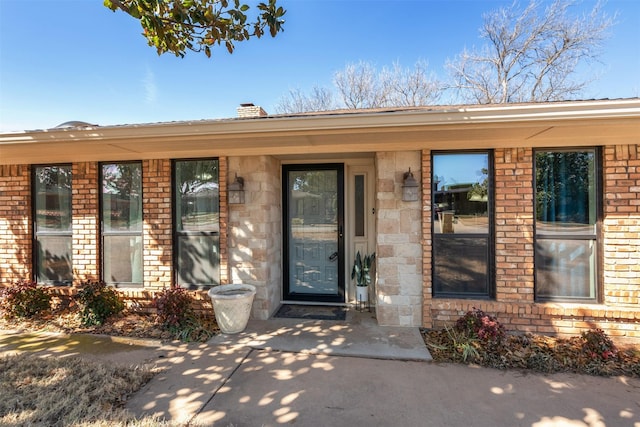 doorway to property with brick siding and a chimney