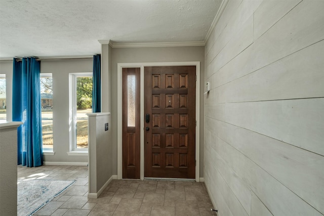 foyer entrance featuring ornamental molding, a textured ceiling, and baseboards