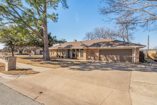 single story home featuring a garage, driveway, brick siding, and a chimney