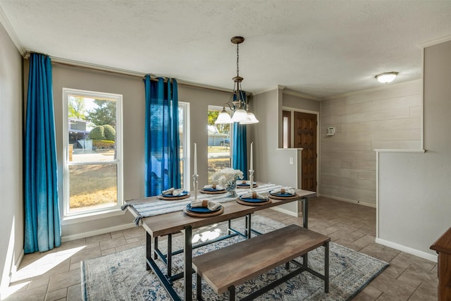 dining space with stone tile flooring, a healthy amount of sunlight, crown molding, and a textured ceiling