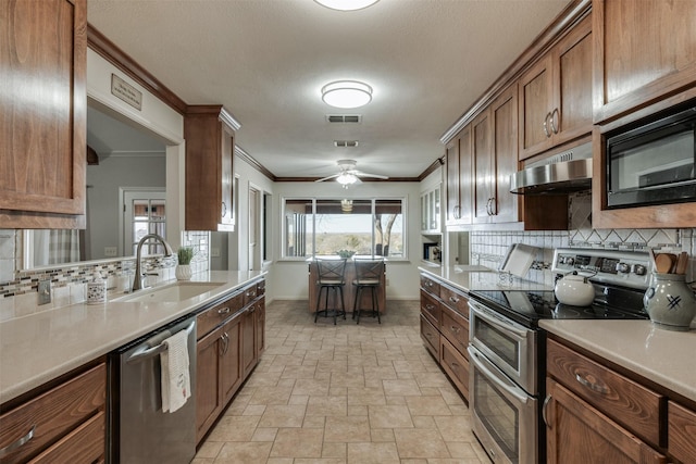 kitchen featuring light countertops, visible vents, appliances with stainless steel finishes, a sink, and under cabinet range hood