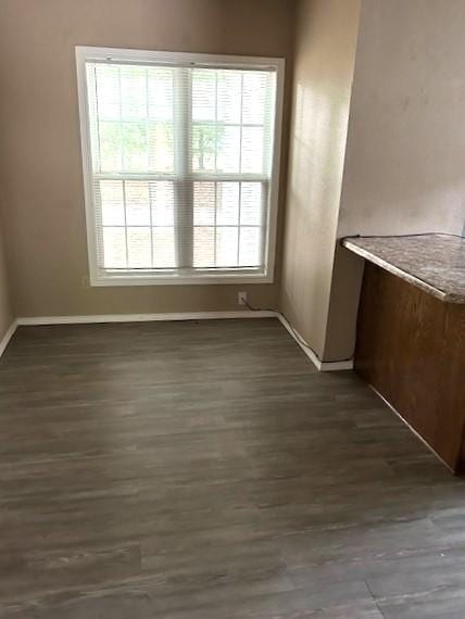 unfurnished dining area with dark wood finished floors and baseboards