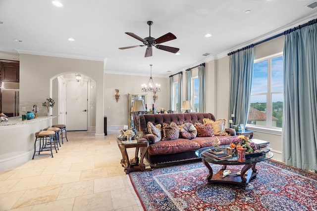 living room with baseboards, arched walkways, crown molding, and ceiling fan with notable chandelier