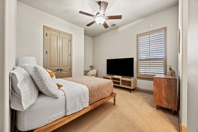 bedroom with a closet, visible vents, light colored carpet, and ceiling fan