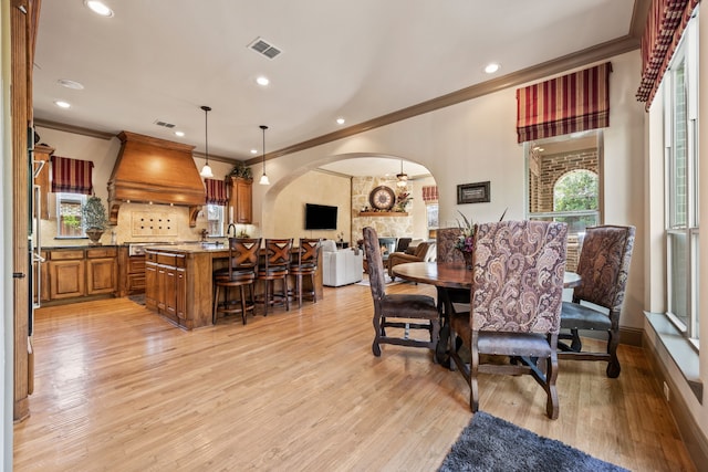 dining space featuring visible vents, crown molding, recessed lighting, light wood-style floors, and arched walkways