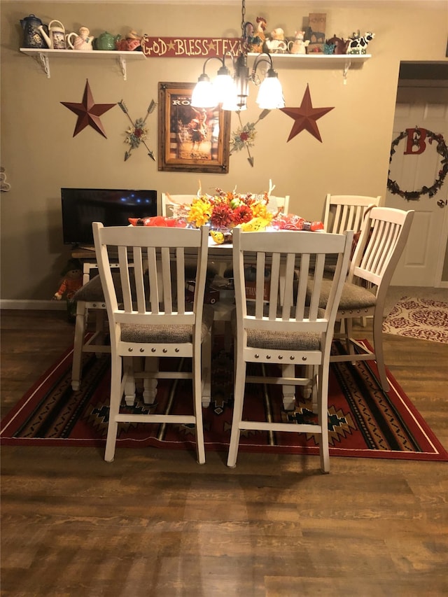 dining area featuring baseboards, wood finished floors, and an inviting chandelier