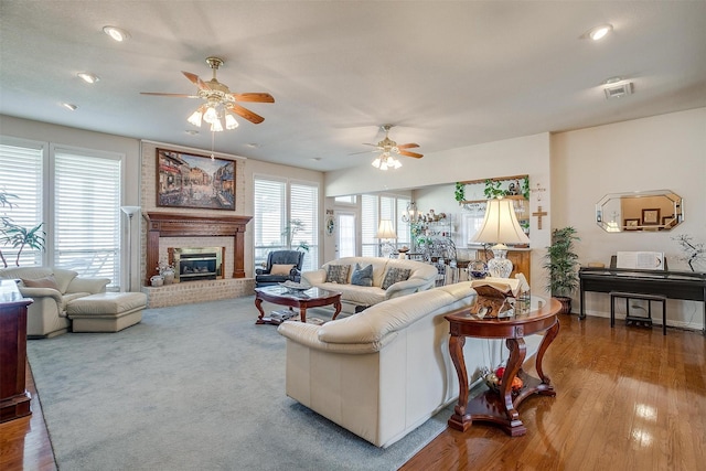 living area with ceiling fan, recessed lighting, wood finished floors, visible vents, and a brick fireplace