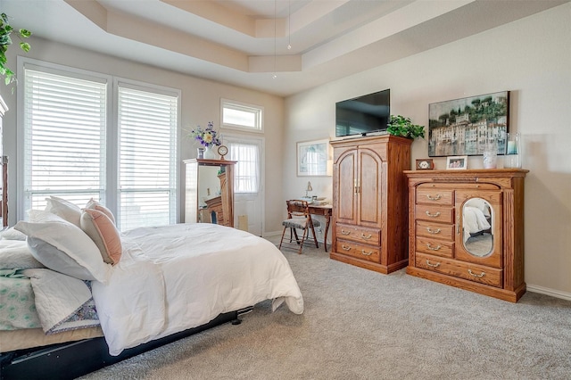 bedroom featuring a tray ceiling, light carpet, and baseboards