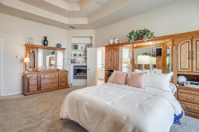 bedroom featuring a glass covered fireplace, light carpet, visible vents, and multiple windows