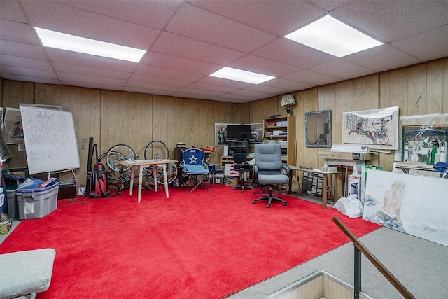 office area with carpet floors, a paneled ceiling, and wooden walls