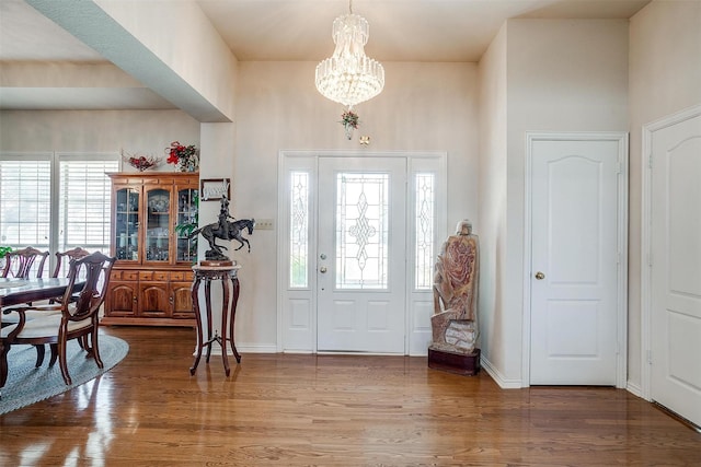 foyer entrance featuring a notable chandelier, baseboards, and wood finished floors