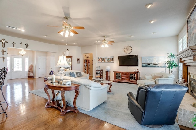 living area featuring light wood-style floors, a fireplace, and visible vents