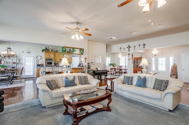 living area with ceiling fan with notable chandelier, wood finished floors, and visible vents