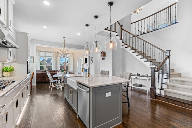 kitchen with gray cabinetry, a sink, a kitchen breakfast bar, open floor plan, and appliances with stainless steel finishes