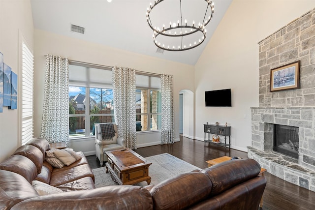 living room featuring visible vents, arched walkways, wood finished floors, and a stone fireplace