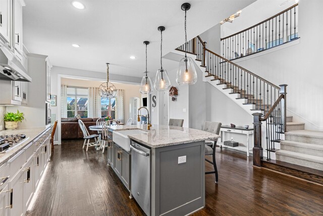 kitchen with open floor plan, a kitchen bar, dark wood-type flooring, a sink, and gray cabinetry