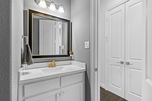 bathroom with a textured wall, wood finished floors, and vanity