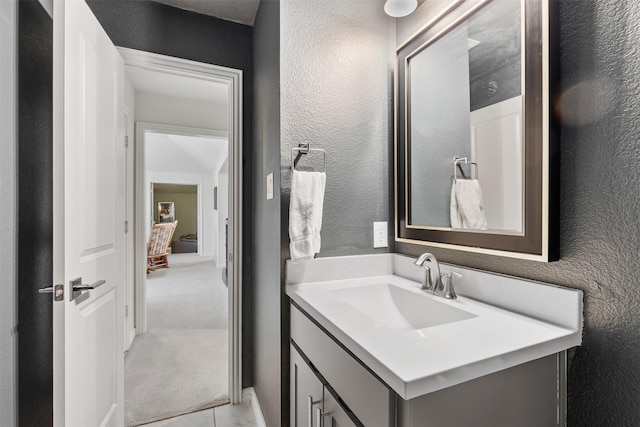 bathroom with a textured wall and vanity