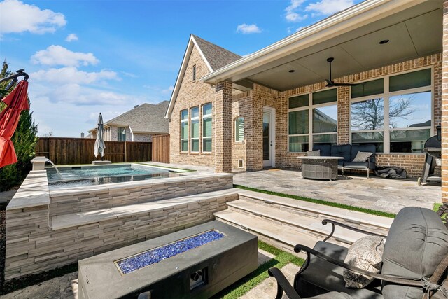 view of patio / terrace with a fenced backyard, an outdoor fire pit, and a jacuzzi