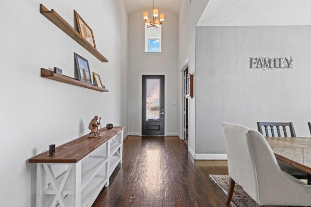 foyer entrance with baseboards, a high ceiling, wood finished floors, and a chandelier