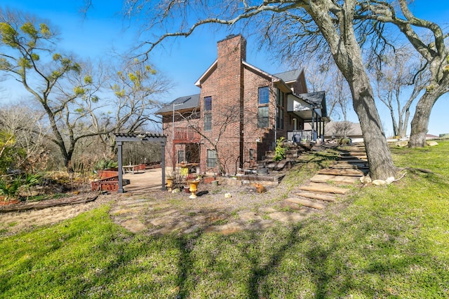 view of property exterior featuring brick siding, a patio, a chimney, a lawn, and a pergola