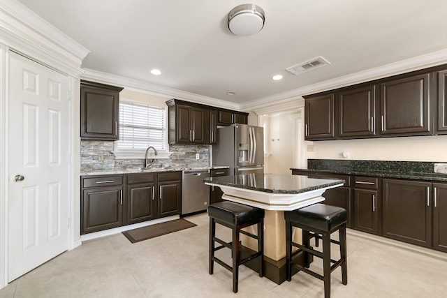 kitchen with crown molding, visible vents, appliances with stainless steel finishes, a sink, and dark brown cabinetry