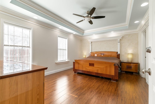 bedroom featuring dark wood-type flooring, a raised ceiling, and ornamental molding