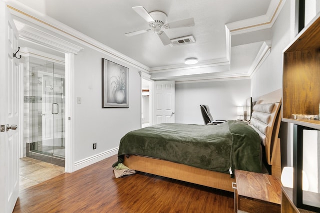 bedroom with connected bathroom, wood finished floors, visible vents, baseboards, and crown molding