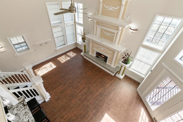 living area featuring baseboards, a fireplace, a ceiling fan, and wood finished floors