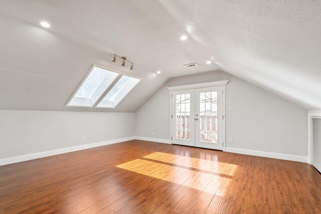 additional living space with lofted ceiling, wood finished floors, visible vents, and baseboards