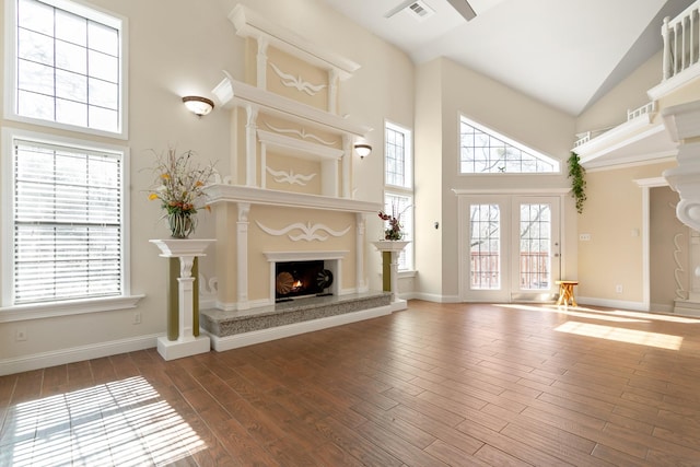 unfurnished living room featuring visible vents, high vaulted ceiling, wood finished floors, and a high end fireplace