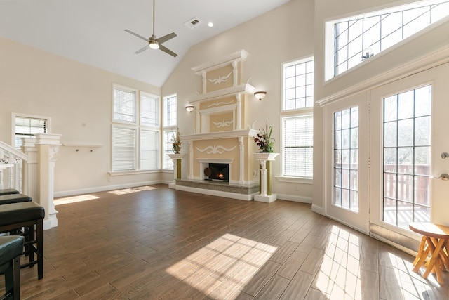 living room featuring a lit fireplace, high vaulted ceiling, wood finished floors, and visible vents