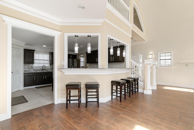 kitchen featuring dark wood-style floors, fridge with ice dispenser, a breakfast bar area, and ornamental molding