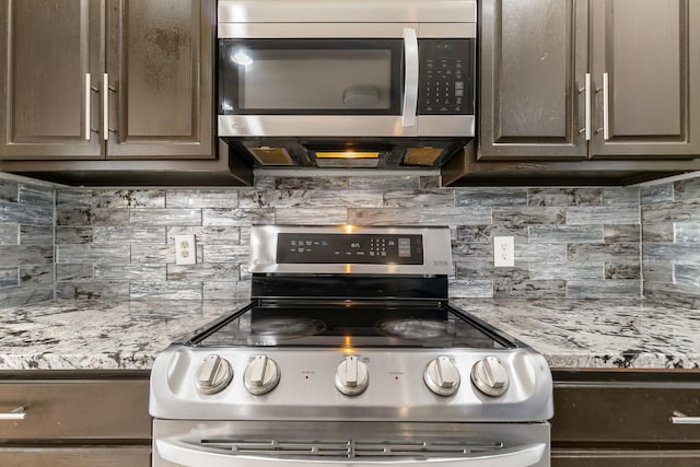 kitchen featuring stainless steel appliances, dark brown cabinets, light stone countertops, and decorative backsplash