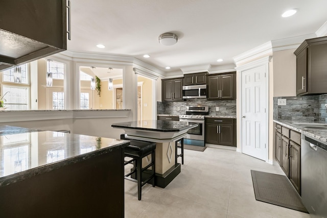 kitchen featuring stainless steel appliances, ornamental molding, and dark brown cabinetry