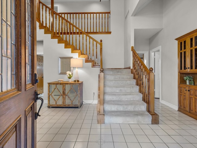 foyer entrance featuring stairs, light tile patterned flooring, and baseboards