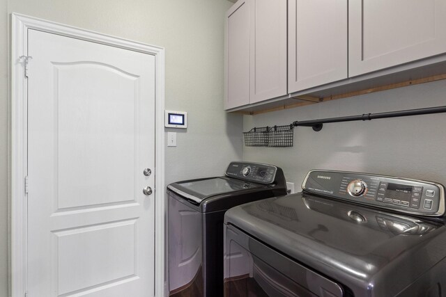 clothes washing area featuring washer and dryer and cabinet space