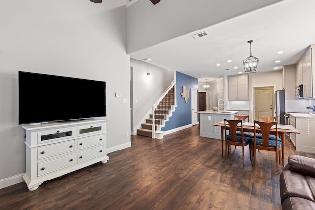 living room featuring baseboards, visible vents, dark wood-style floors, stairway, and a notable chandelier