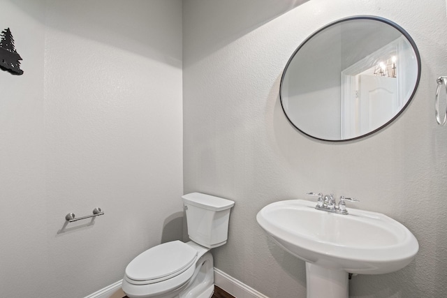 bathroom featuring baseboards, a sink, and toilet